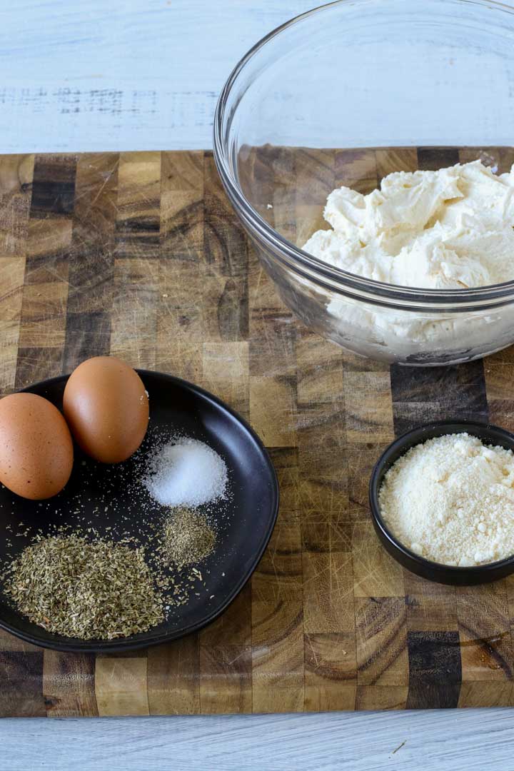 Ricotta cheese, eggs, parmesan cheese and spices on a cutting board