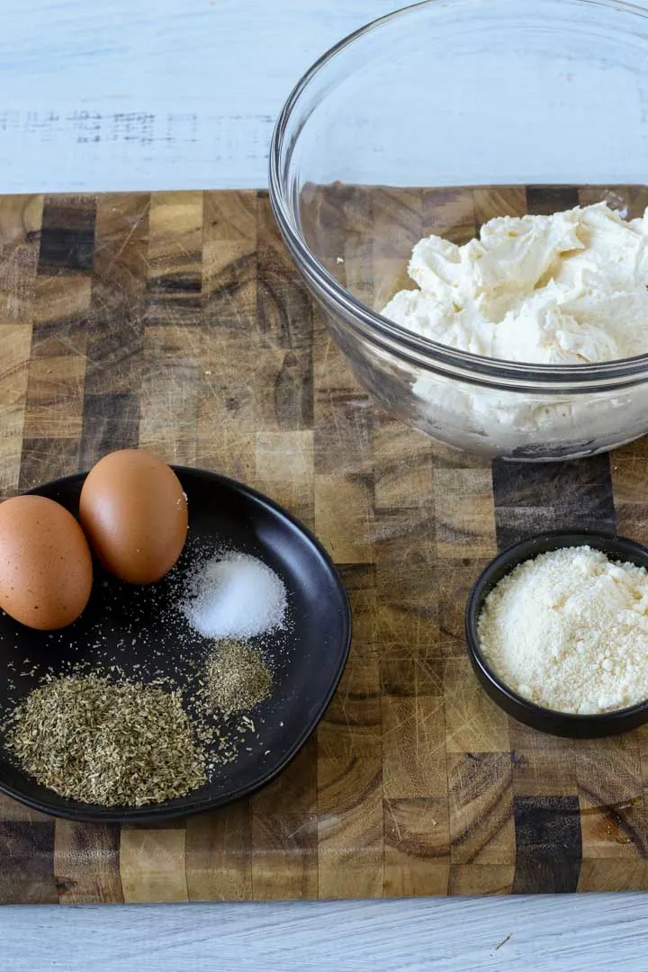 Ricotta cheese, eggs, parmesan cheese and spices on a cutting board